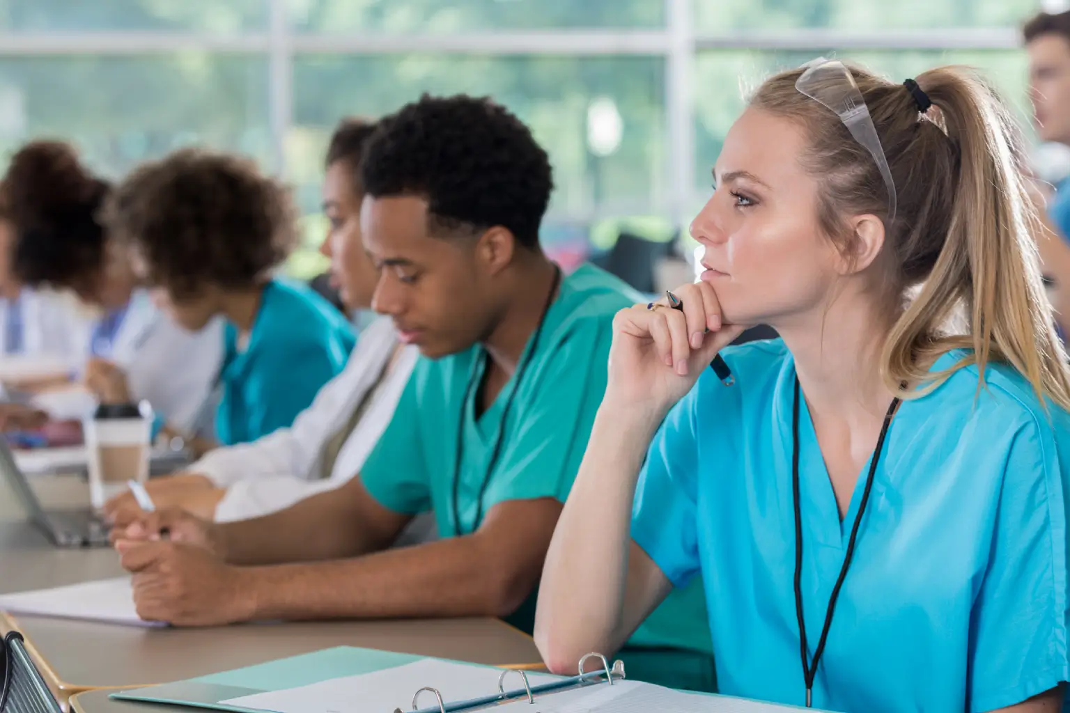 Medical students attentively listening in a classroom.