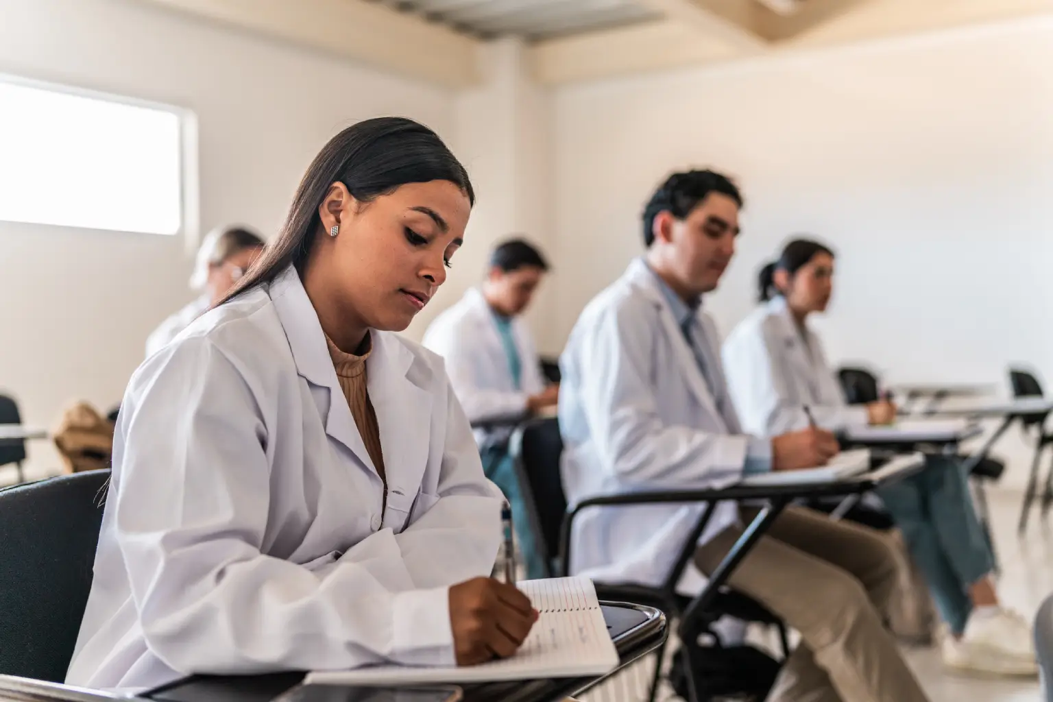 Students in lab coats taking notes.