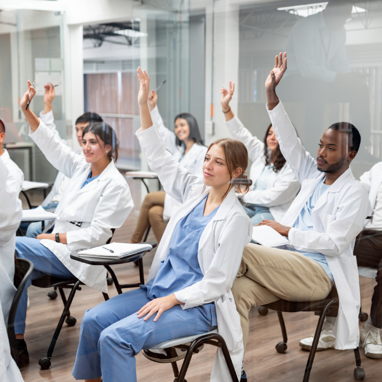 Medical students raising hands in classroom.