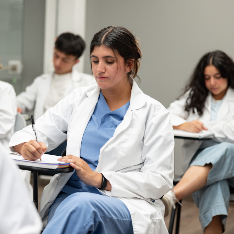 Medical students writing notes in class.