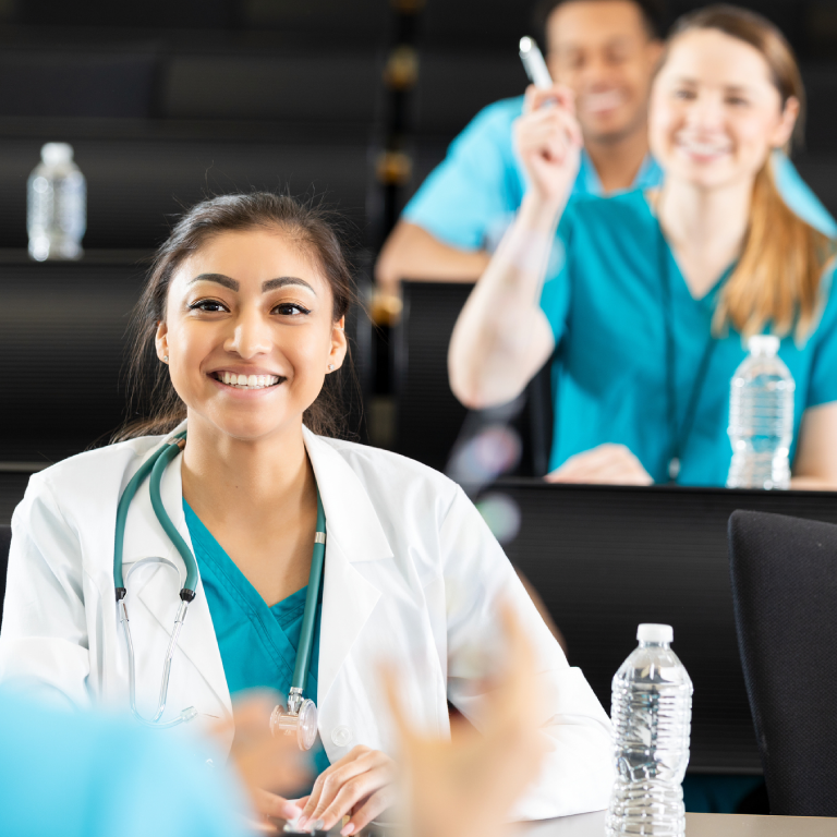 Medical students in lecture room, smiling.