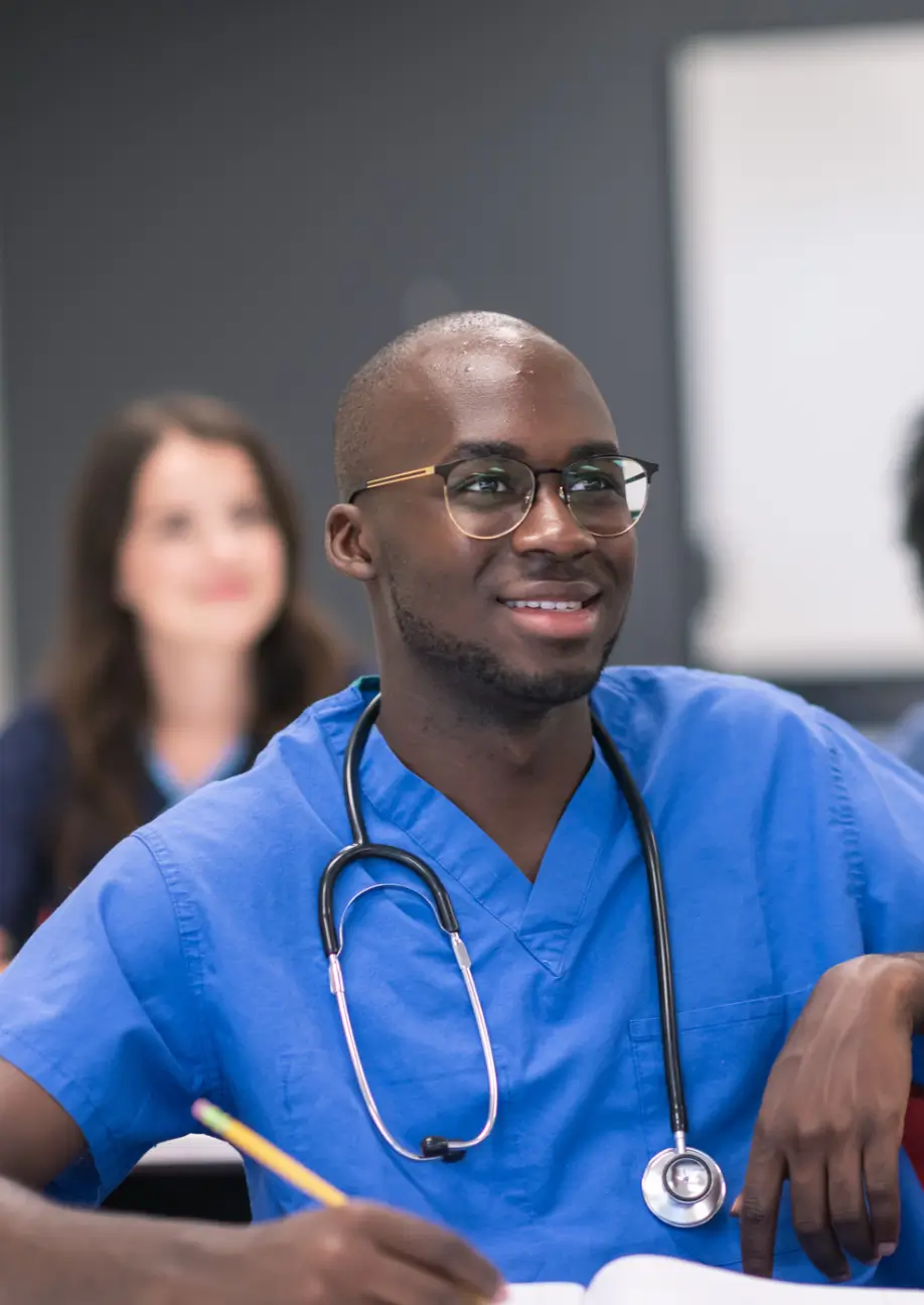 Medical student in blue scrubs smiling.