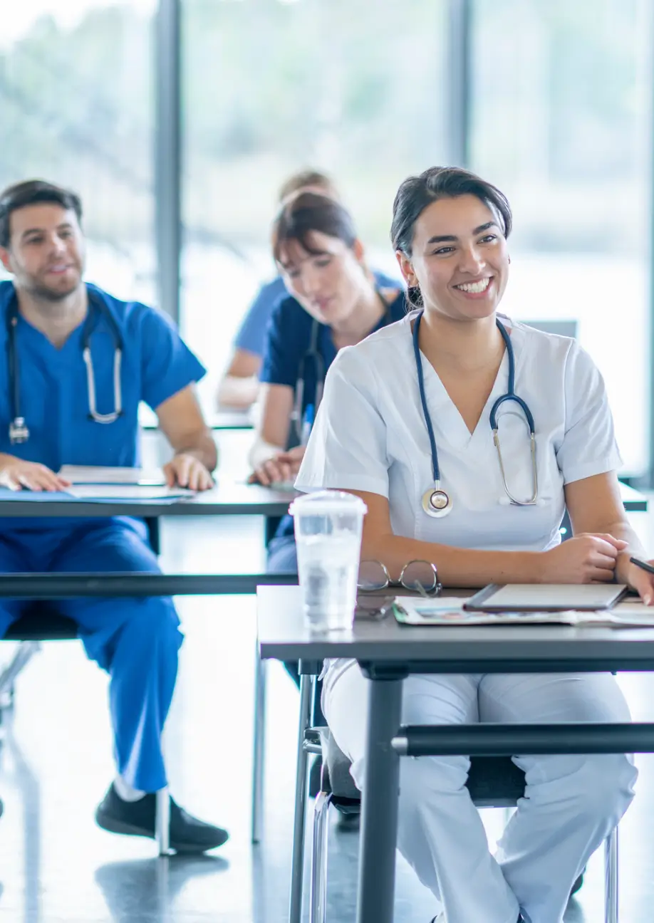 Medical students in classroom, wearing scrubs.