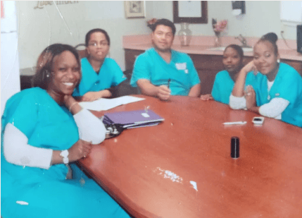 Five medical staff in teal scrubs meeting