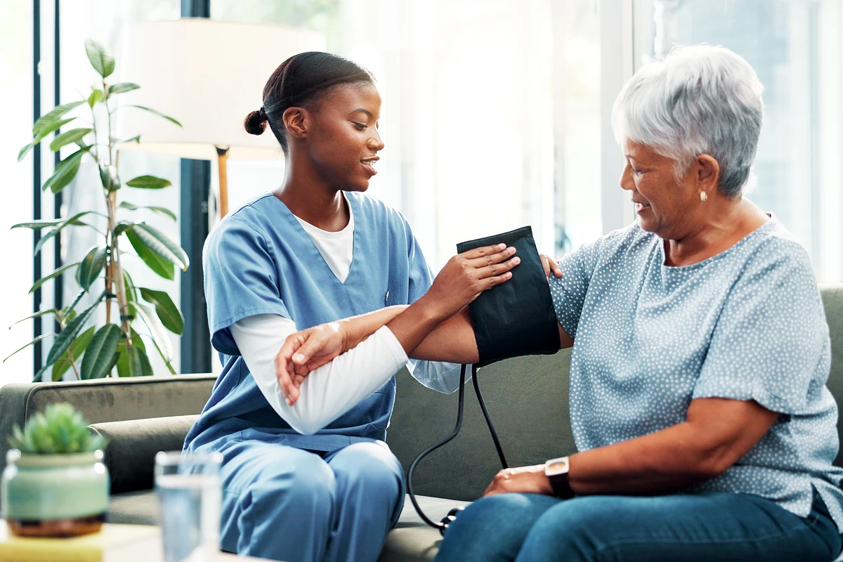 Nurse checking elderly woman's blood pressure.