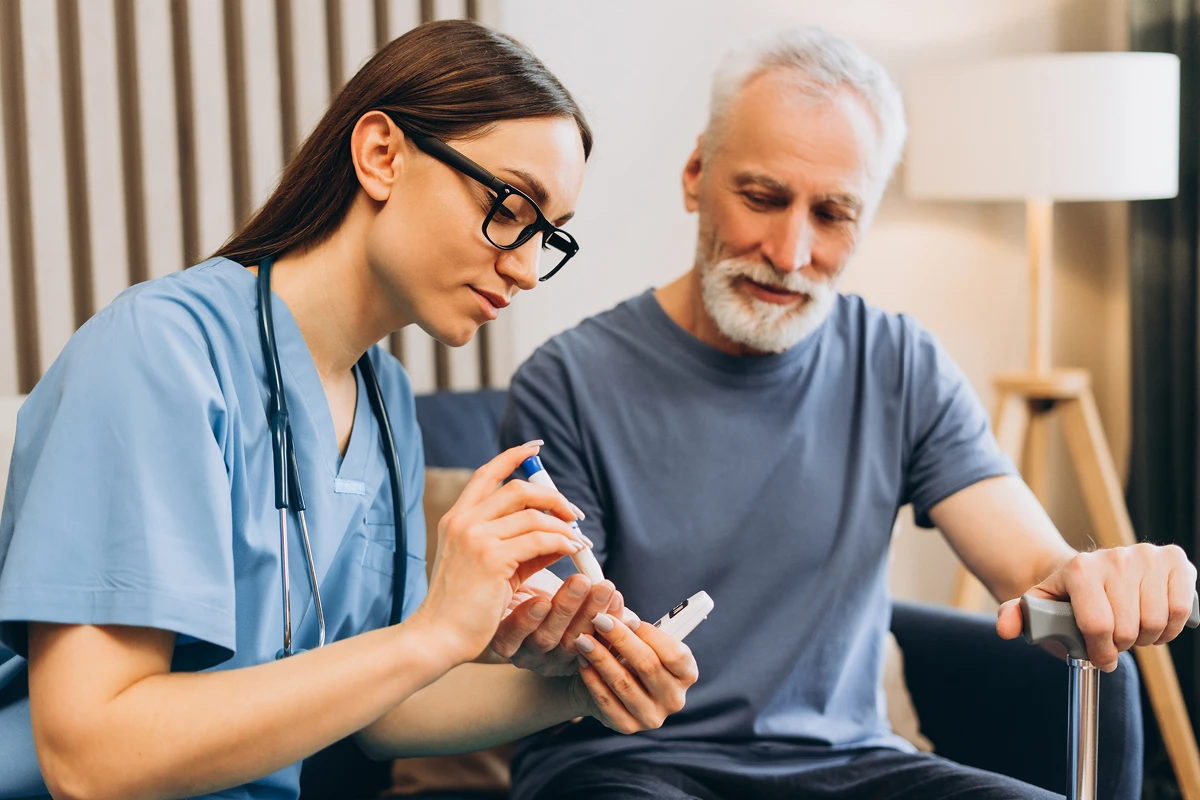 Nurse assisting elderly man with diabetes test.