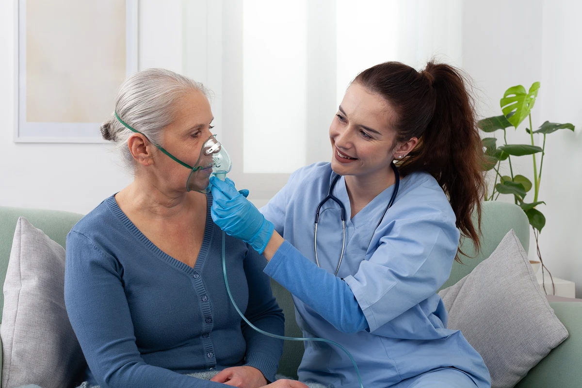 Nurse assisting elderly woman with oxygen mask.